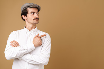 Image closeup of caucasian mustached man wearing hat pointing finger at copyspace