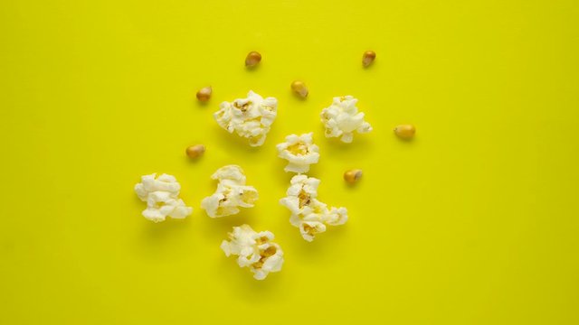 Stop motion creative concept video footage food popcorn seeds on yellow background.