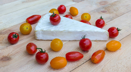 Naklejka na ściany i meble Cheese and colorful red, orange and yellow cherry tomatoes on wooden background. 