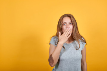 brunette girl in gray t-shirt over isolated orange background shows emotions