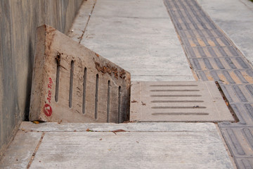 Sewage drain with open concret grate on the sidewalk. Sewer manhole.