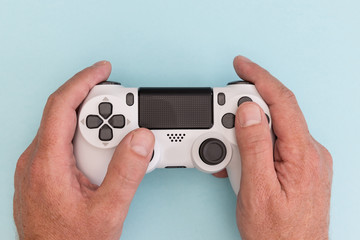 Video games man playing white gaming controller in hands isolated on blue color background top view