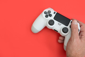 Video games man playing white gaming controller in hands isolated on red color background top view