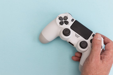 Video games man playing white gaming controller in hands isolated on blue color background top view