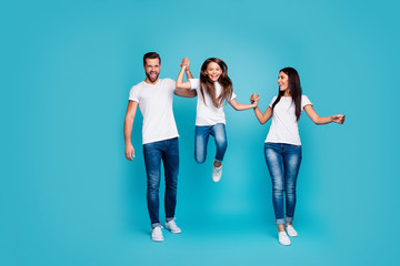 Naklejka premium Full size photo of daddy mommy and small lady going and jumping together wear casual outfit isolated blue background