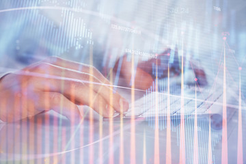 Double exposure of graph with man typing on computer in office on background. Concept of hard work.