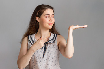 People and emotions. A young brunette in a blouse smiling and points her hand and finger to the...