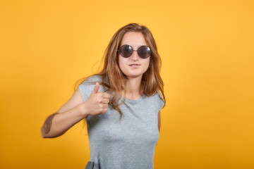 brunette girl in gray t-shirt over isolated orange background shows emotions