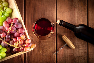 Cellar Tasting. A photo of a red wine glass with a bottle, grapes, and a vintage corkscew, shot from the top on a dark rustic wooden background - Powered by Adobe