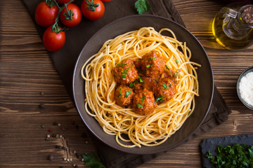 Delicious spaghetti with meatballs in tomato sauce on dark background, italian cuisine