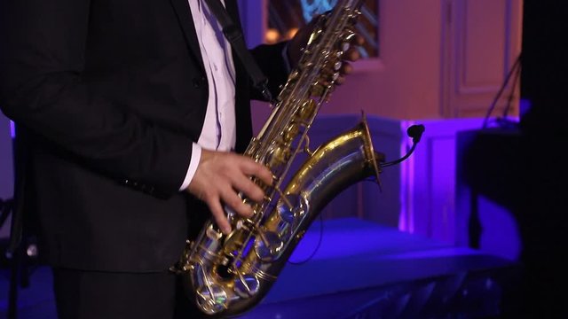 Saxophonist in dinner jacket play on saxophone. Live performance. Jazz music.