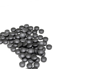 black pills of activated carbon on white background. SUPPLEMENT tablet