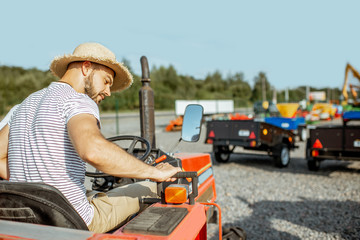 Young agronomist with elegant salesman choosing a tractor for farming on the open ground of agricultural shop