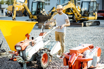 Obraz na płótnie Canvas Agronomist choosing farm cultivator machine at the outdoor ground of the shop with agricultural machinery