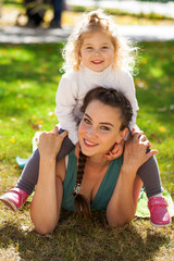 Closeup portrait of a young beautiful mother with little curly daughter in autumn park
