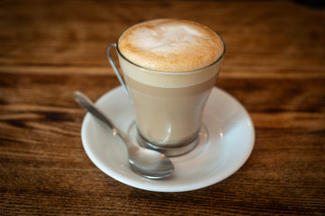 Latte coffee in a glass cup on a wooden cafe table