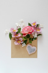Pink floral composition in the brown envelope on a white background
