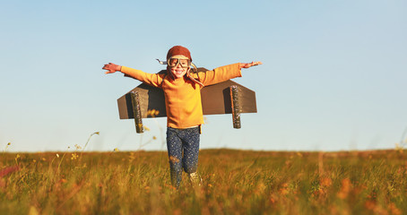 Child pilot aviator with wings of airplane dreams of traveling in summer  at sunset