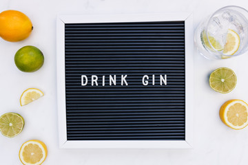 Gin tonic cocktail drink in glass with message word letters on white marble minimal background