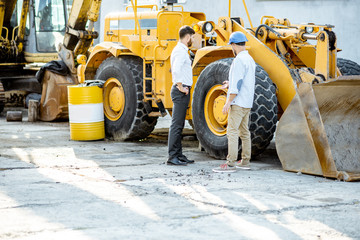 Builder choosing heavy machinery for construction, talking with a sales consultant on the open...
