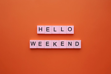 Hello weekend word wooden cubes on an orange background.