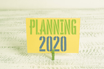 Text sign showing Planning 2020. Business photo showcasing Begin with end in the Mind Positioning Long term Objectives Green clothespin white wood background colored paper reminder office supply