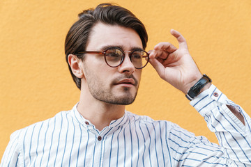 Image of young confident man wearing eyeglasses looking aside at copyspace