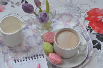 tray with paper sketchbook, smartphone and spring flowers on pink bedding. Relaxing, or working, or writing diary or blog in bed at home.