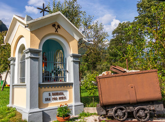 Saint Barbara Chapel with mining Vehicle near Graveyard and Mining Tunnel in Log pod Mangartom, Bovec, Slovenia, Europe.
