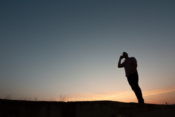 Fototapeta premium silhouette of man with cell phone at sunset
