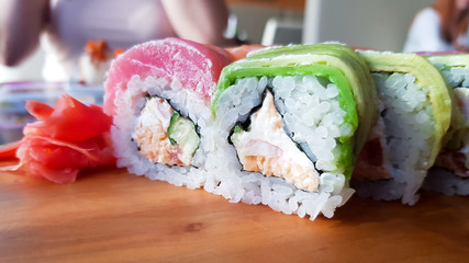 Rainbow sushi roll with salmon, eel, tuna, avocado, king prawns. Beautiful serve in the restaurant. Sushi menu. Japanese food
