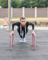 Athletic girl push ups on a street playground