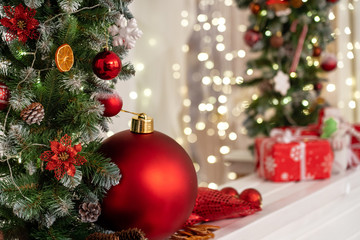 Christmas gifts and a big red ball lie under a fir garland decorated with snowflakes balls of dried oranges. the boxes are decorated with ribbons. New year cozy background. beautiful postcard