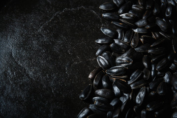 Black fried sunflower seeds on a dark background. Low key photography. Top view with space for copy.