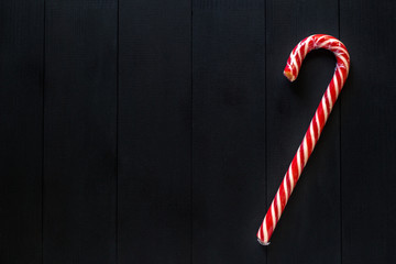 one candy cane lie on a black wooden table.
