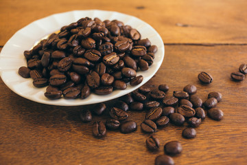 Coffee beans in a white plate on a wooden table