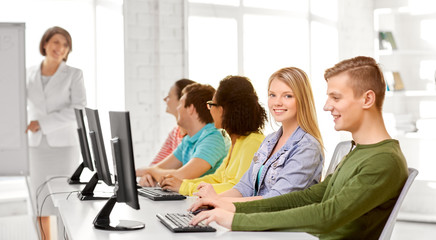 Obraz premium education, technology and learning concept - group of happy international high school students or classmates in computer class