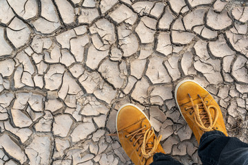 Human legs standing on dried cracked earth