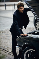 Young man in black suit opened mask and checking engine car