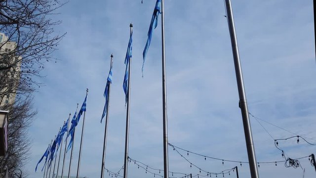 Row of flagpoles each with a blue striped flag that is gently blowing in a light breeze