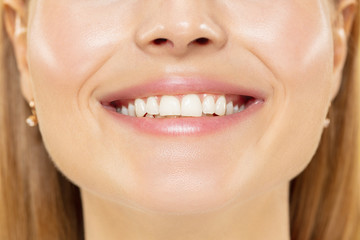 Obraz premium Close up shot of young woman on yellow studio background. Beautiful female model with well-kept skin. Concept of human emotions, facial expression, beauty, healthy lifestyle. Lips, teeth smiling.