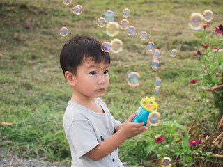 Asian Thai little kid boy playing bubbles with natural background. Happy and freedom time.