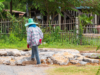 A woman labor worker standing on pile of broken cement.