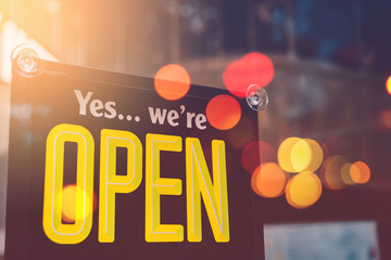 Open sign hanging front of cafe with colorful bokeh light abstract background.