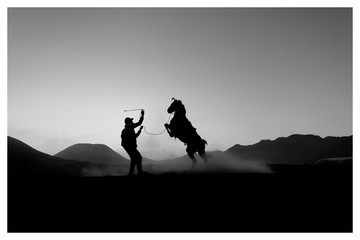 BROMO, INDONESIA. AUGUST 6TH, 2019 : Silhouette of Bromo Horseman action for camera at the mountainside of Mount Bromo, Semeru, Tengger National Park, Indonesia.