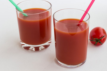 Two glasses of tomato juice on a white background