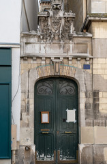 Old door. Ancient facade building with gorgeous antique black door in Paris France. Historic architecture building entrance with sculptural arch above ornate shabby door. Baroque style architecture 