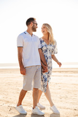Photo of funny nice couple laughing and holding hands together while walking on sunny beach
