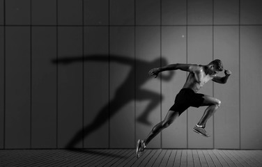 Athletic man sprinter running on dark wall background - 289306238
