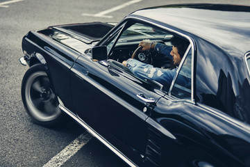 A man driving old black stylish car - Powered by Adobe